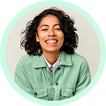 Mulher negra de cabelo preto e cacheado. Utiliza uma camisa verde.